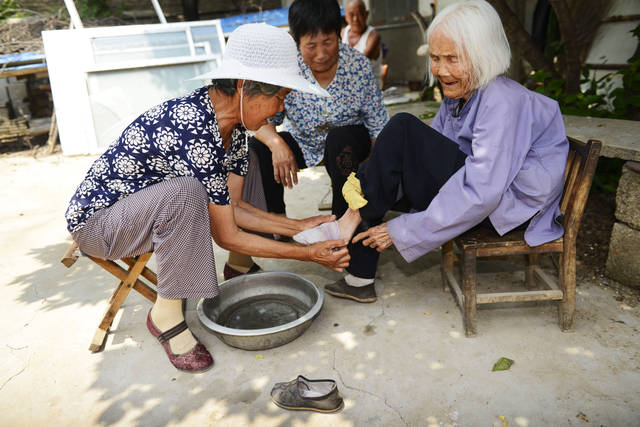 小脚老人王臻桂在女儿薛彦迎(左一),大儿媳赵修梅的帮助下洗脚.