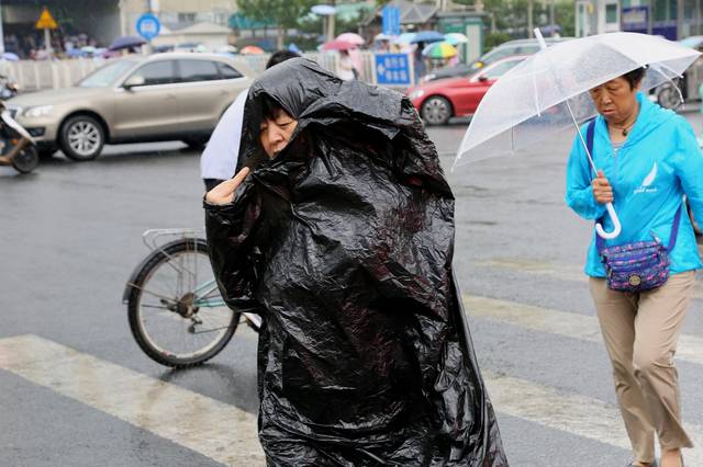 马路上的一位行人,直接将黑色塑料袋包在身上避雨.尉森茂 摄