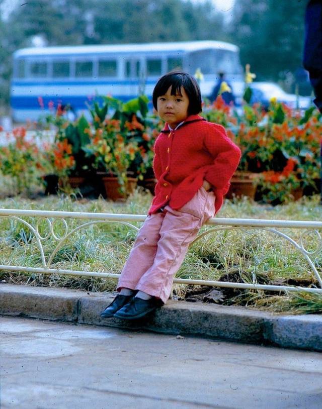 1983年的儿童们:可爱的小女孩坐在路边花栏杆上