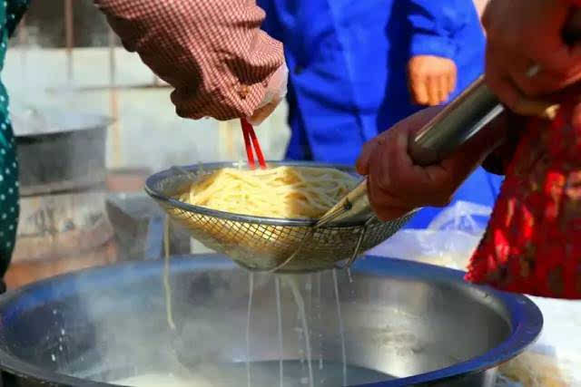 制作者用饸饹床子(做饸饹面的工具,有漏底)把和好的面团放在饸饹床子