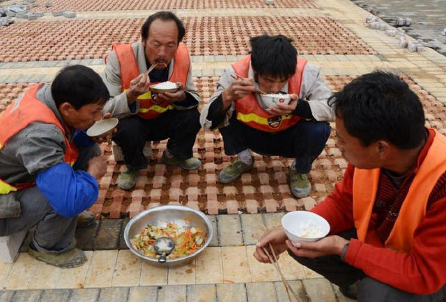 2016年4月27日,在北京通州的一处工地上,吃中午饭的民工用塑料袋盛饭