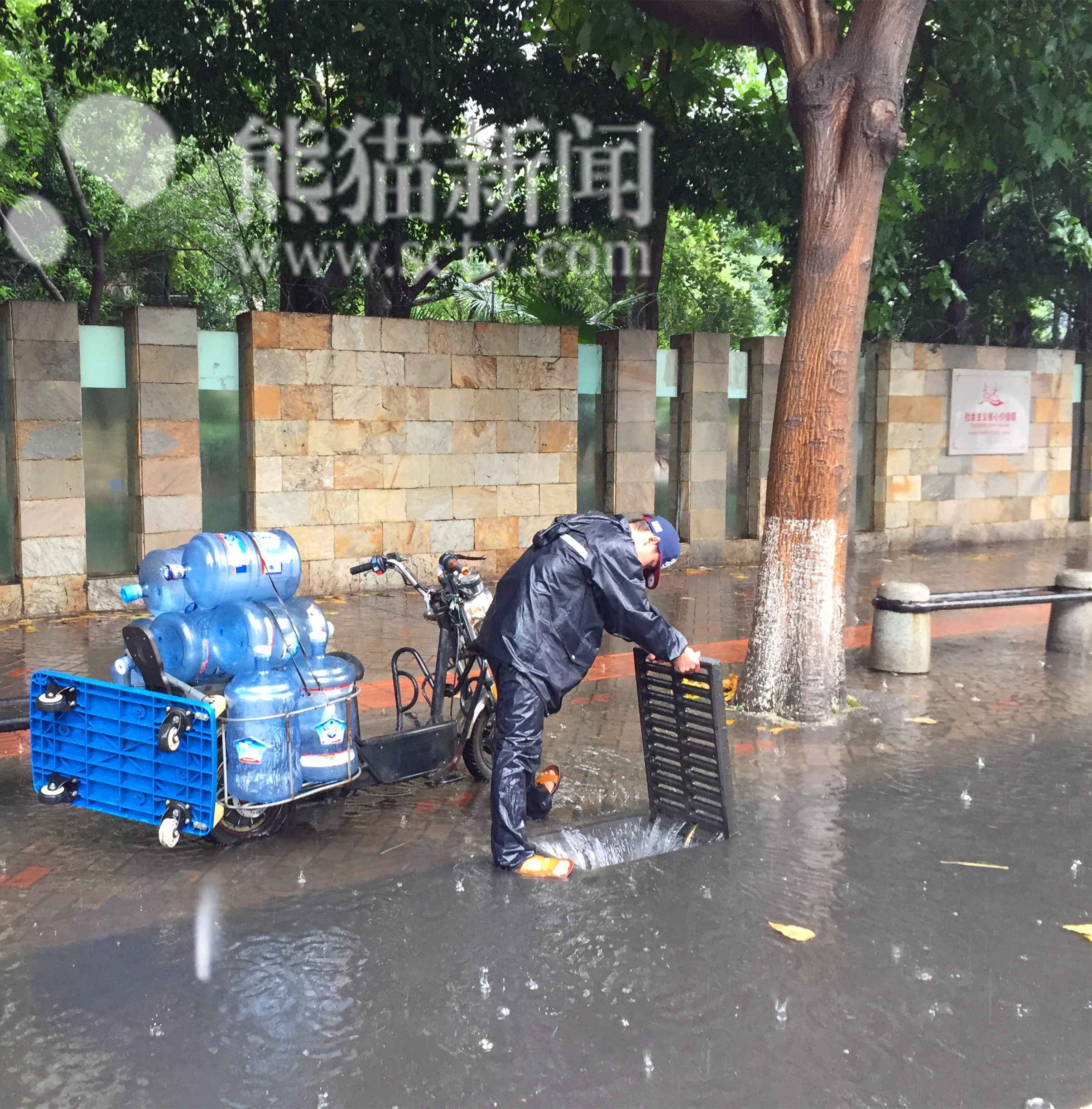 大雨中,一名送水小哥载着桶装水骑着电动车,经过一处积水路段的时候