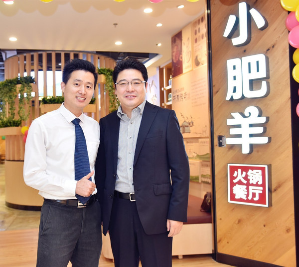 沈宇豪(右)与小肥羊店长共庆上海莲花路新店开业.