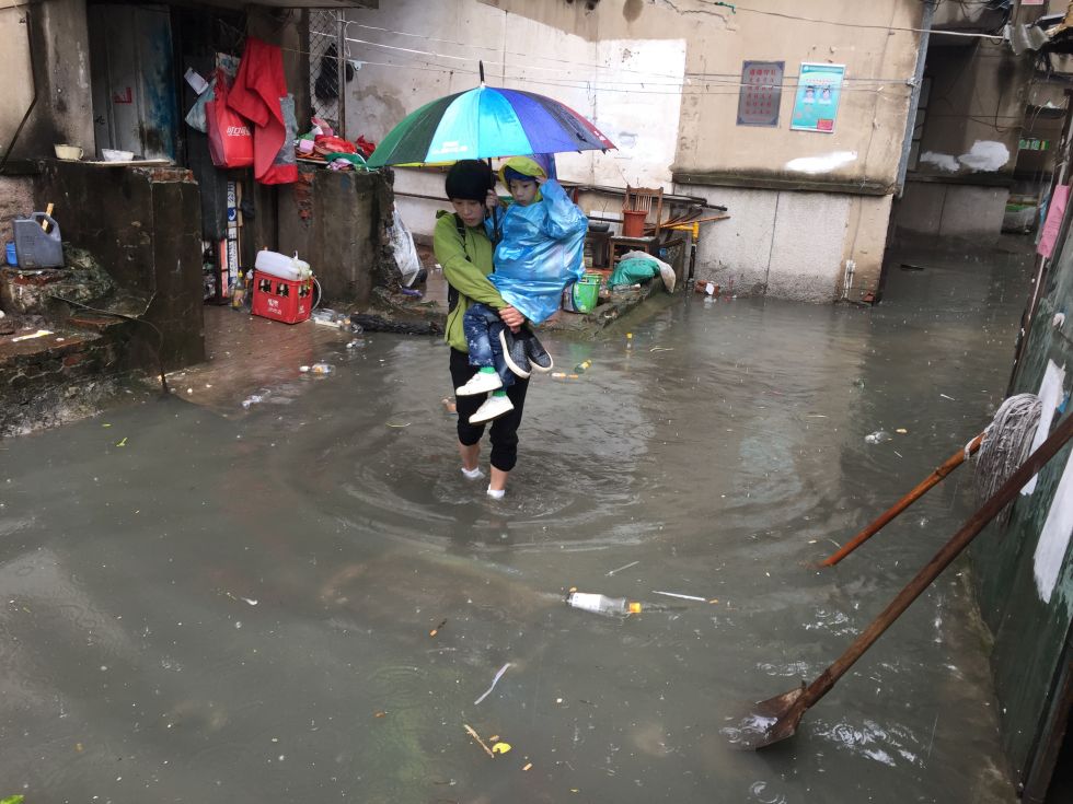 合肥大雨致阜阳路一旧小区内涝女子趟水送孩子上学