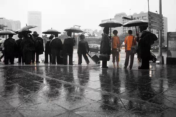 直立在信义区一角撑着雨伞的上班族,是雕刻大师朱铭的幽默,却也是雨中
