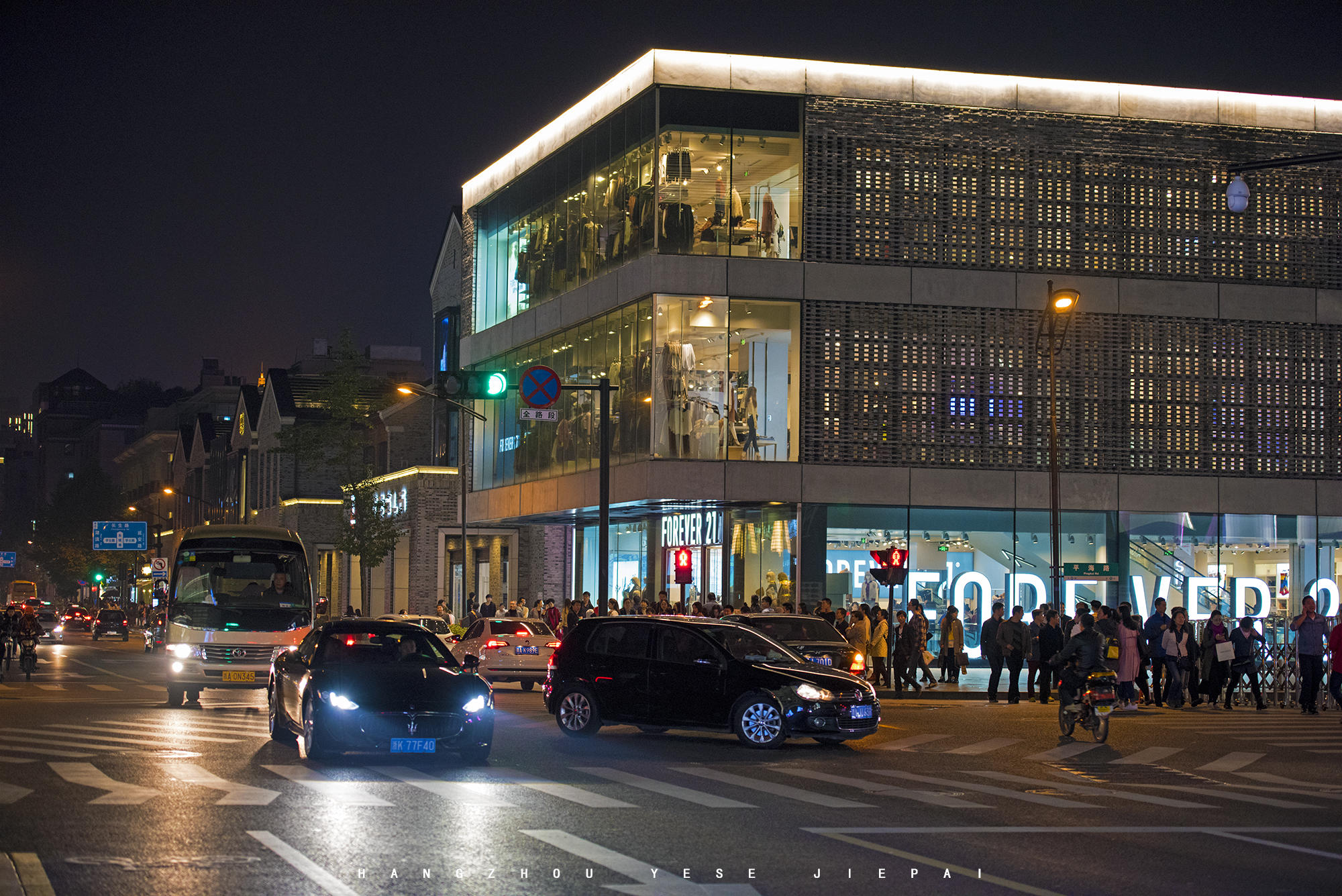 图为杭州夜晚的街景,东坡路红绿灯旁的人们,繁华地段人来人往