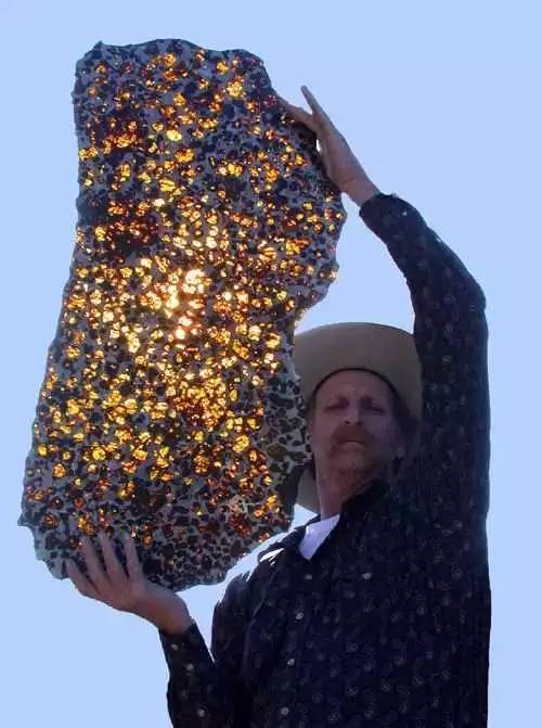 男子展示这块大陨石,看起来像是一个蜂窝状的灯箱.