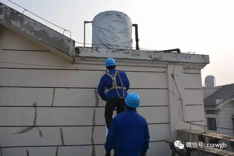 施工人员需经过顶楼居民家中才能爬上楼顶,为水箱穿上防冻衣