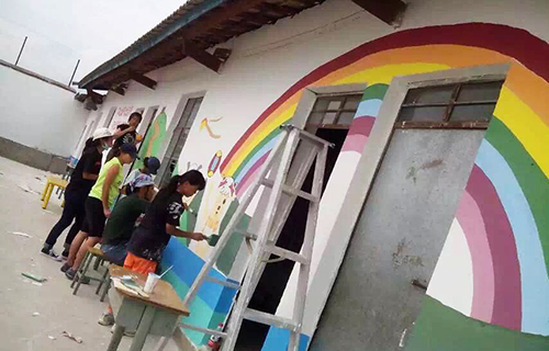 图为阿苏英雄和老师们给教室的外墙刷彩虹的颜色