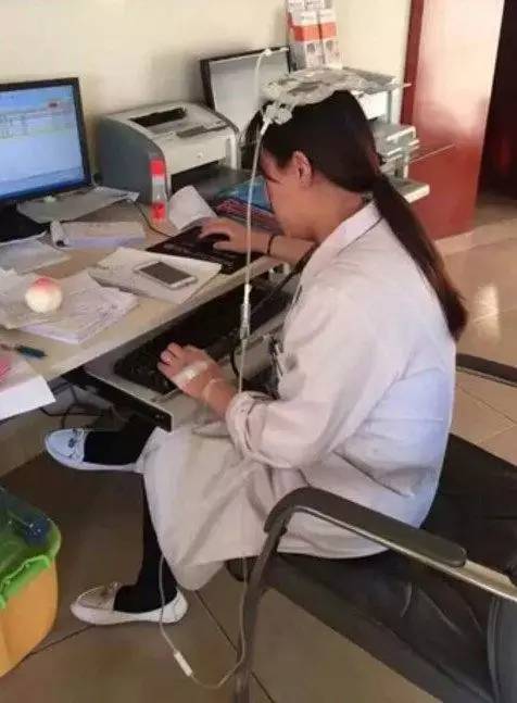 近日,沈阳市妇婴医院儿科医生头顶输液袋打点滴,带病坚持工作的图片