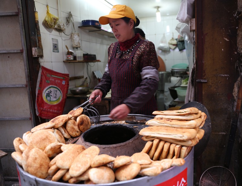 这是一家无名的烧饼店,80年后的老铁炉,一炕就炕了几十年的烧饼,至贴