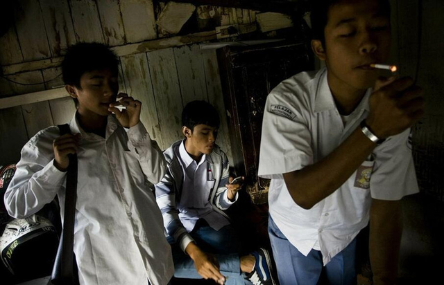 图为印尼的青少年们聚在一起抽烟,有样学样,这些孩子就在这样一种环境