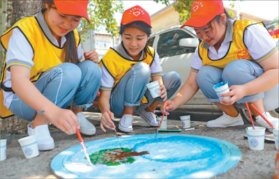 河北秦皇岛市的大学生志愿者社区,使用画笔在小区的120多个井盖上绘画