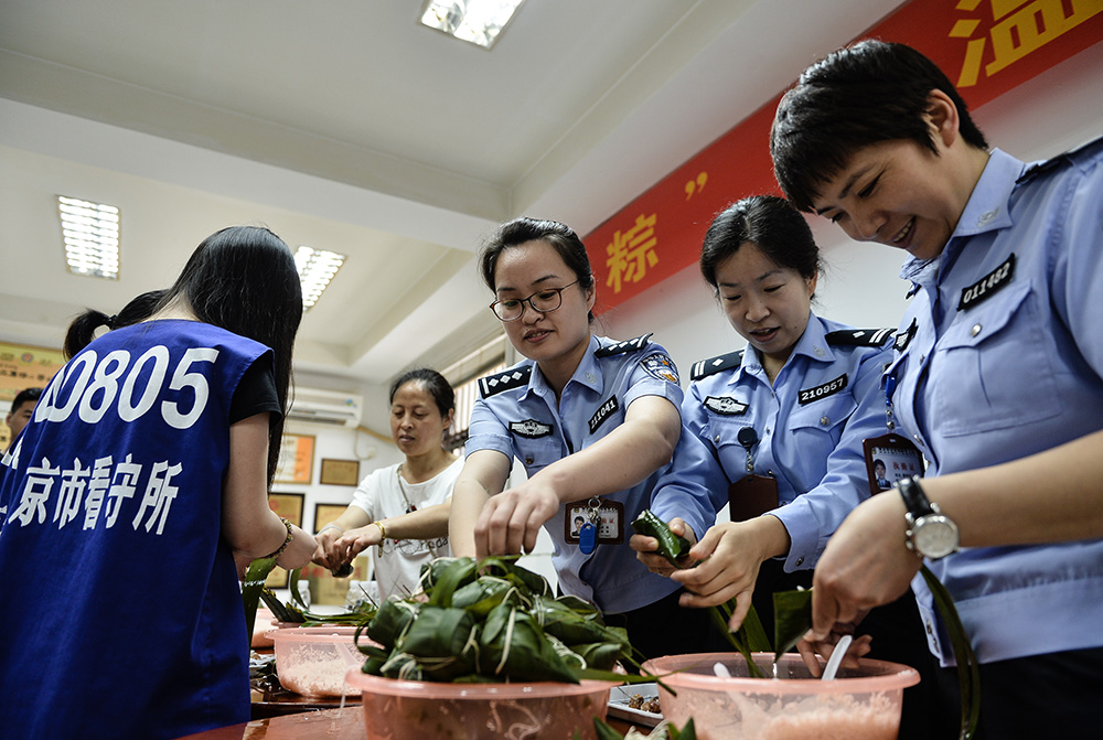 社会 正文  图:民警在南京市看守所与在押人员及其家属在一起包粽子