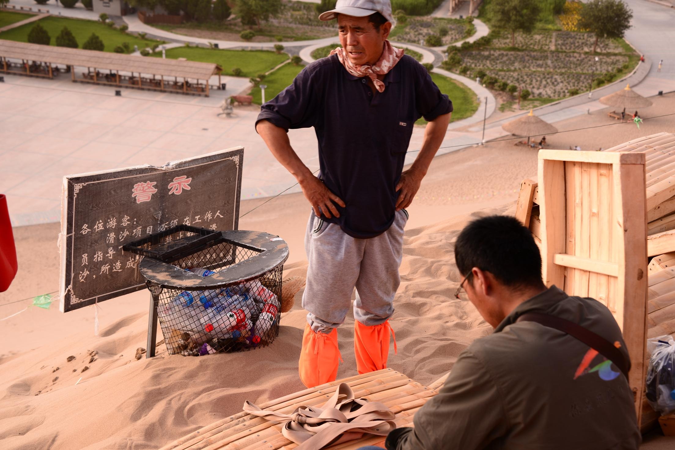 月牙泉脚夫每天给游客背100斤滑沙竹板上山近百趟