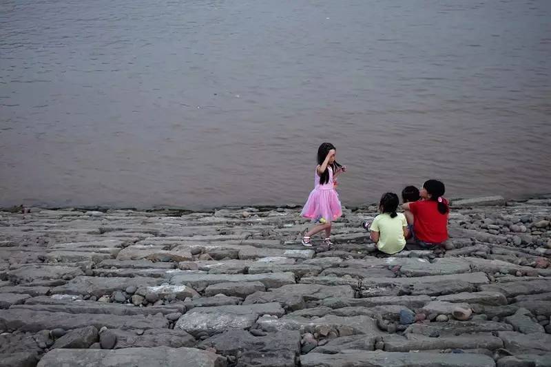 图为三位小女孩在防洪堤上玩耍