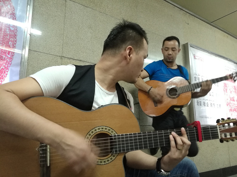 乌鲁木齐两帅哥弹吉他用音乐给市民送凉爽
