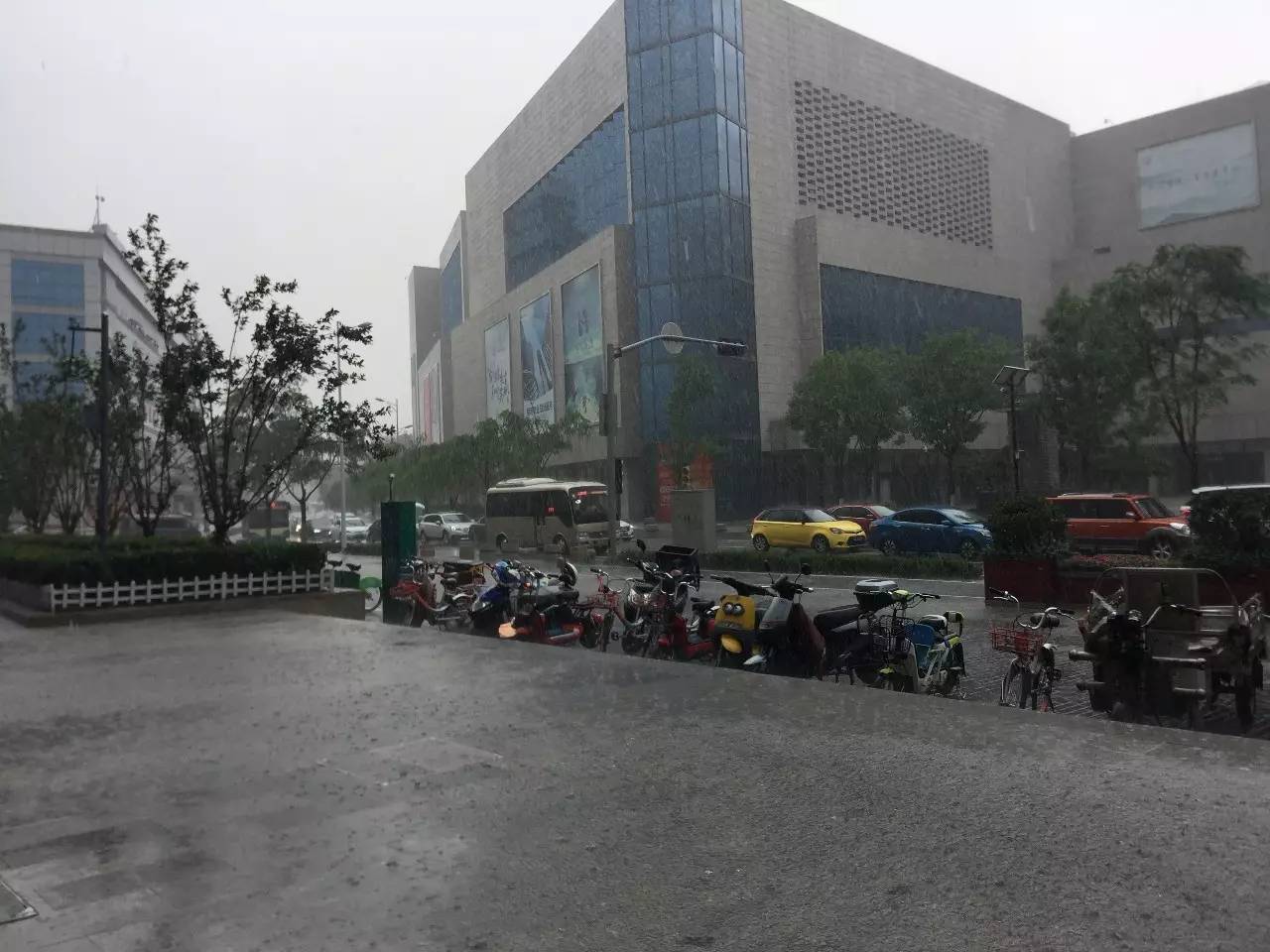 没带雨具的路人躲在公交车站历山路花园路交叉口,风雨里的外卖小哥