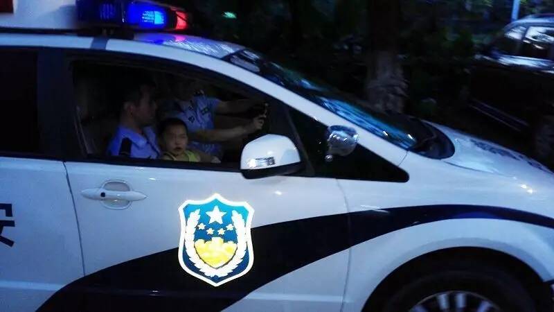 民警立即把警车开到马路中央拦停过往的车辆,下车把小孩抱回警车.