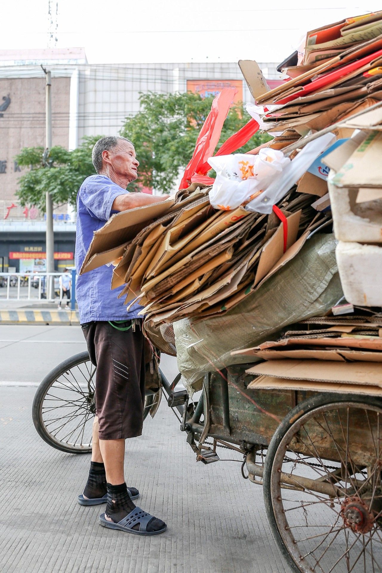 顺着前十这条街我们接着往前走,一辆收废品的车旁,一位大爷满脸汗珠正