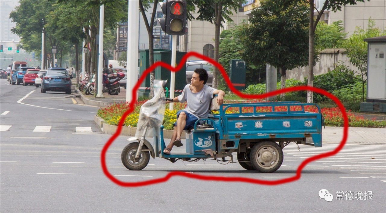 龙港路与紫缘交叉路口路人翘着二郎腿斜坐着开三轮车过红绿灯.