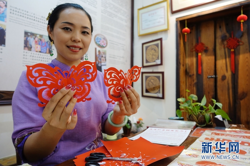 饶宝莲在佛山南风古灶工作室中展示完成的剪纸作品蝴蝶.