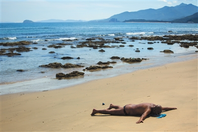 海南万宁市兴隆镇,一位患者独自一人躺在海滩晒太阳.图片