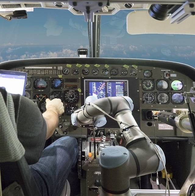 驾驶舱内部,一个有着细长机械臂的机器人在操作着飞机