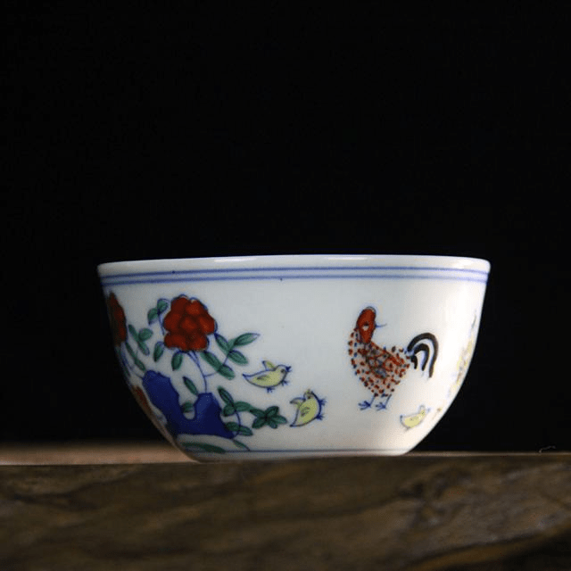 大明成化斗彩鸡缸杯 覆彩:在釉下青花已画成的图案上,按照一定意图