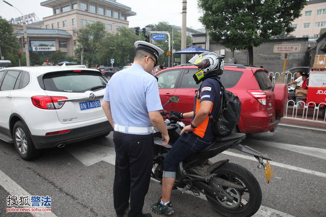 一辆京b号牌摩托车被民警拦下,因京b号牌摩托车全天禁止在北京四环路