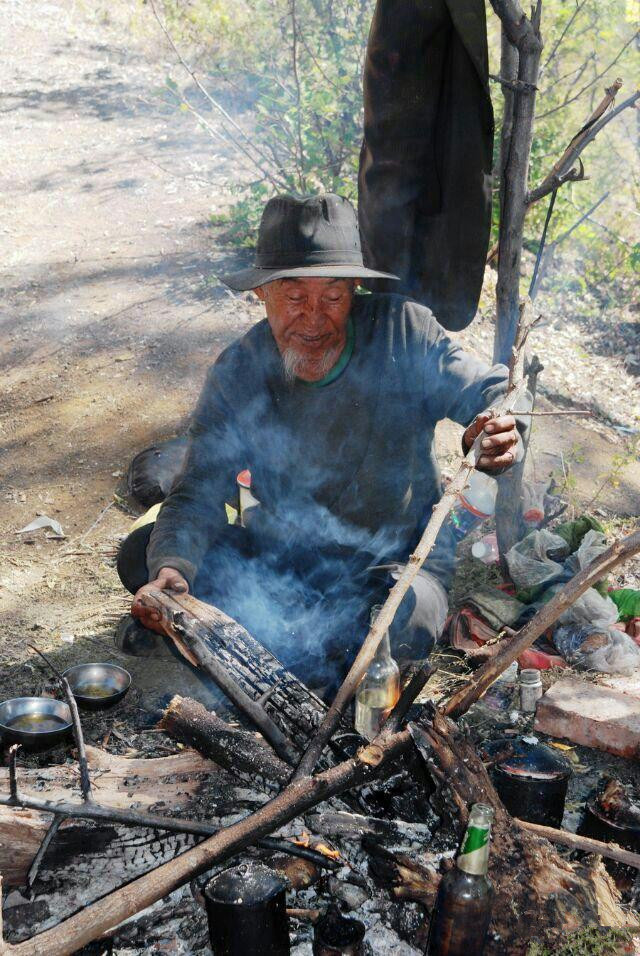 在四川盐源境内的泸沽湖畔烤鱼烤肉的彝族老人,原始的生产,生活方式在