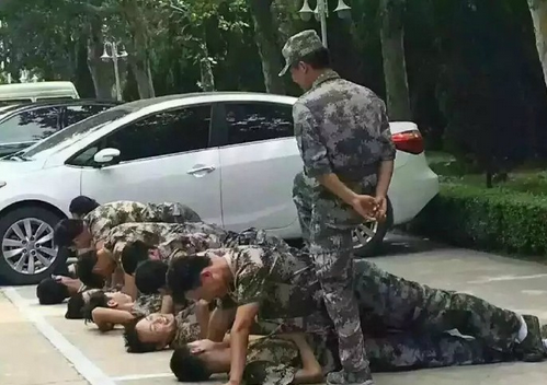 有教官军训为了严格要求学生,让一个男生躺地上,另一个男生在他上方坐