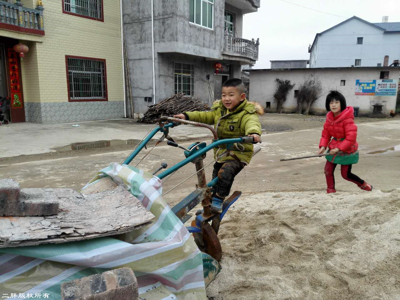 农村孩子的玩耍项目肯定是就地取材的,路边放着的这辆手扶拖拉机已经