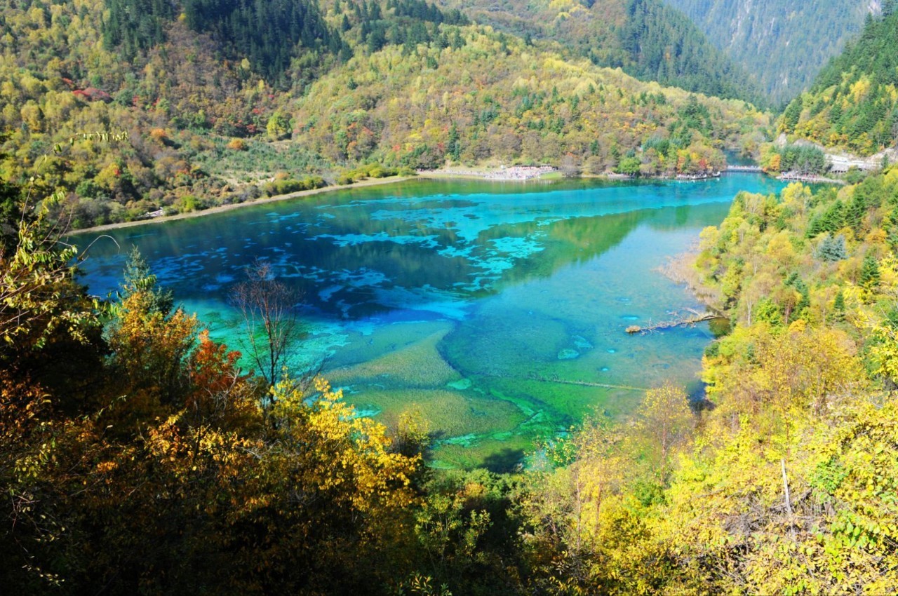 的林木倒影而呈现出五颜六色,在阳光照射下,湖水像宝石一样流光溢彩