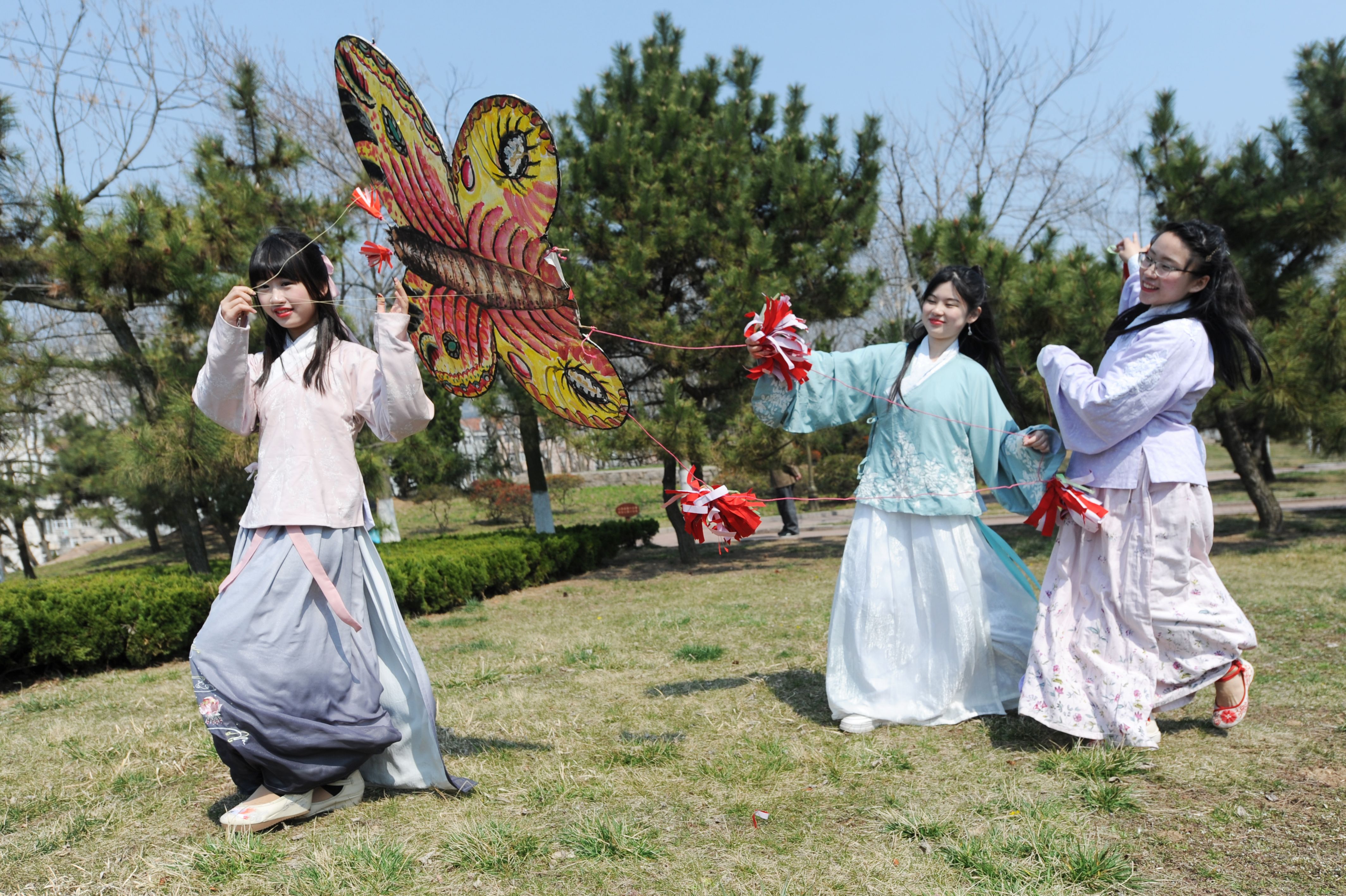 4月1日,山东青岛,几名身穿汉服装扮的少女在清明节活动中放纸鸢(风筝)