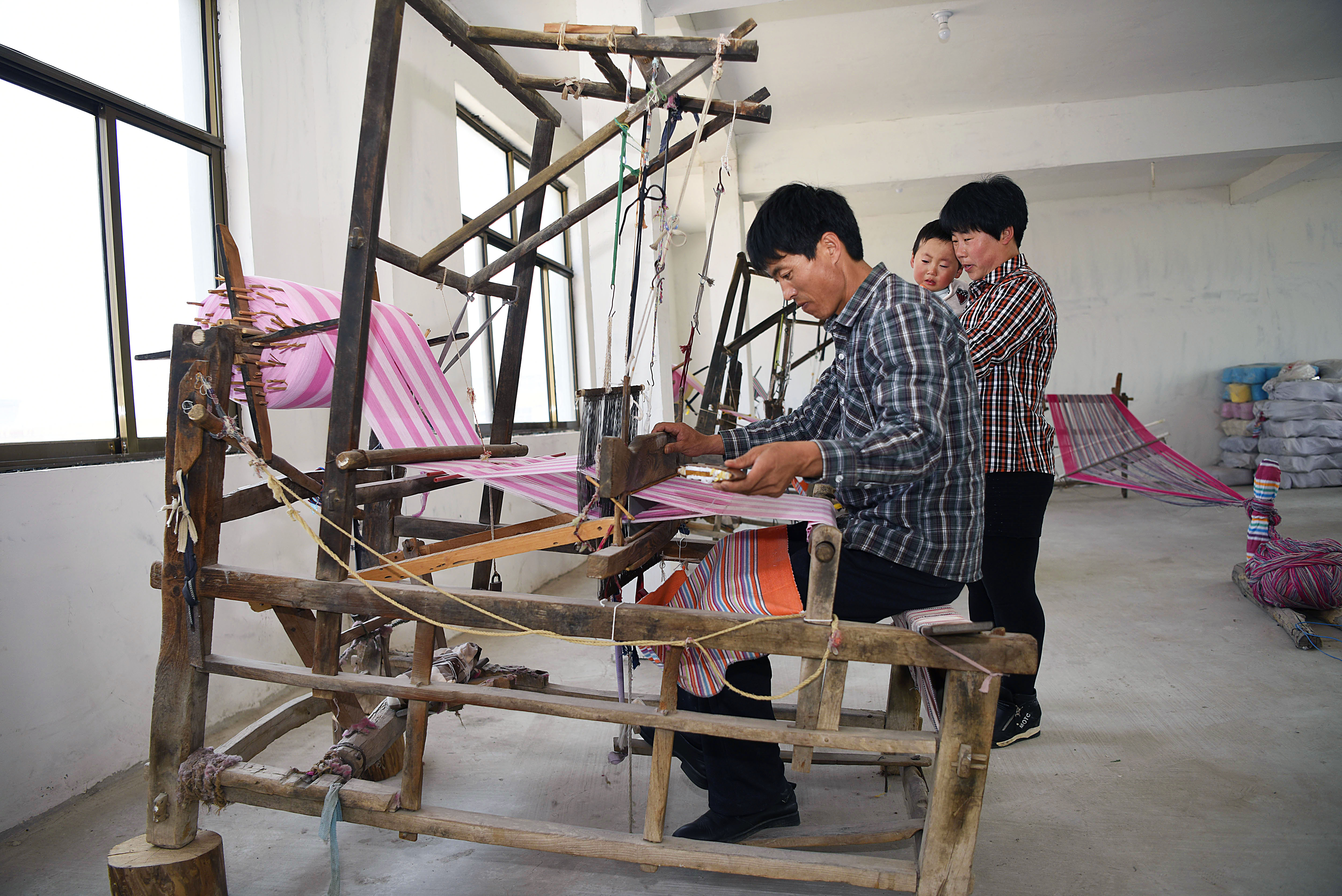 张根芝在利用老木质织布机纺织老粗布