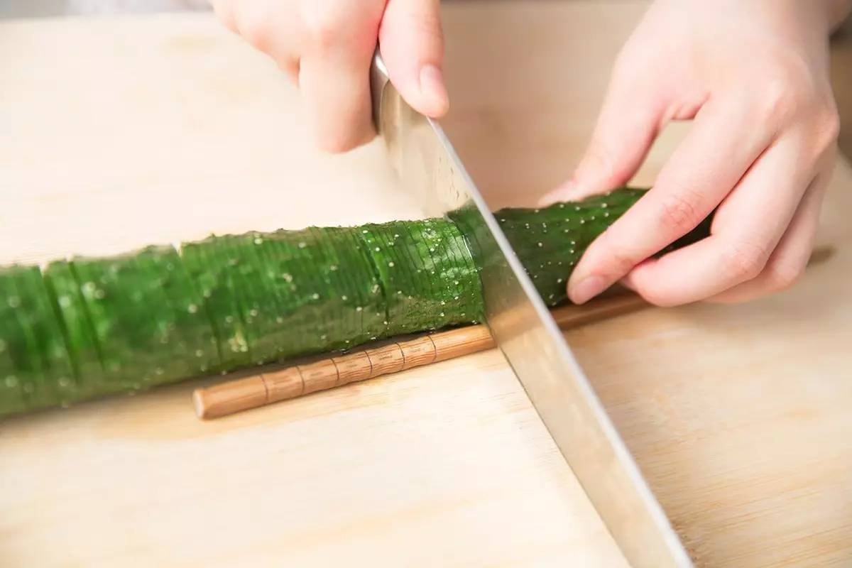 你只需要一双筷子 把筷子放在黄瓜底部两侧 手捏住筷子和黄瓜,用刀