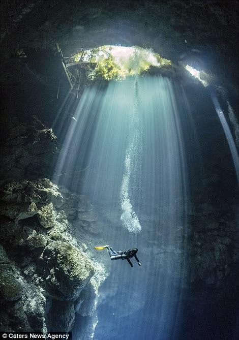 潜入地下:当潜水员们探索洞穴迷宫时,光线从不同的洞中照射进来